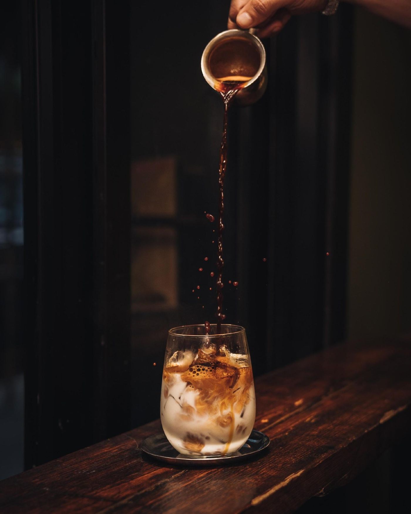 Espresso poured over iced milk in a glass